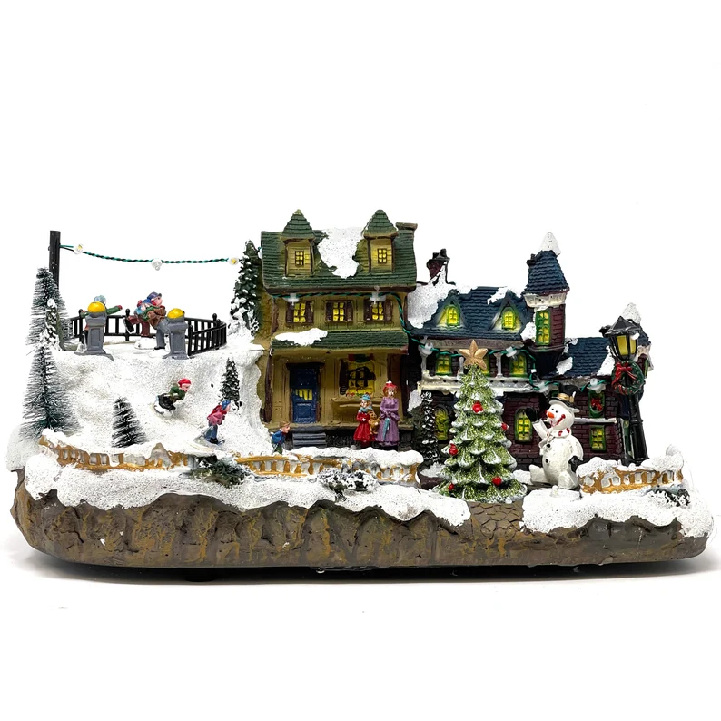 Villa navideña iluminada con nieve, figuras y casitas