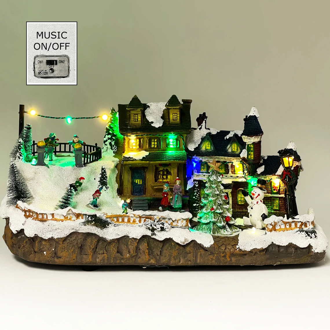 Villa navideña iluminada con nieve, figuras y casitas